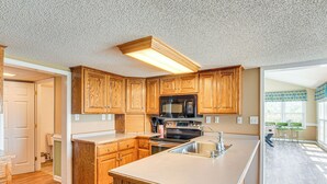 A modern kitchen with wooden cabinets, a stainless steel sink, and a built-in microwave. - 78-Acre Retreat Near Campbell U: Fish, Play, Relax (Coats)