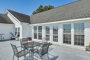 A covered patio with a table and chairs, a potted plant, and a view of a house with large windows and a white exterior. - 78-Acre Retreat Near Campbell U: Fish, Play, Relax (Coats)