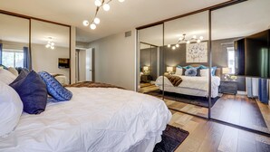 A modern bedroom with a large bed, a mirror, and a ceiling light fixture. - Quiet Henderson Retreat: Extended Stays & Gazebo! (Henderson)