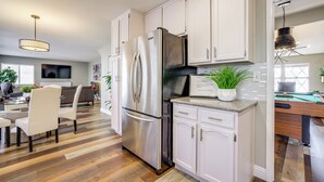 A modern kitchen with white cabinets, stainless steel appliances, and a dining area with a glass table and chairs. - Quiet Henderson Retreat: Extended Stays & Gazebo! (Henderson)