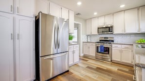 A modern kitchen with white cabinets, stainless steel appliances, and a wooden floor. - Quiet Henderson Retreat: Extended Stays & Gazebo! (Henderson)
