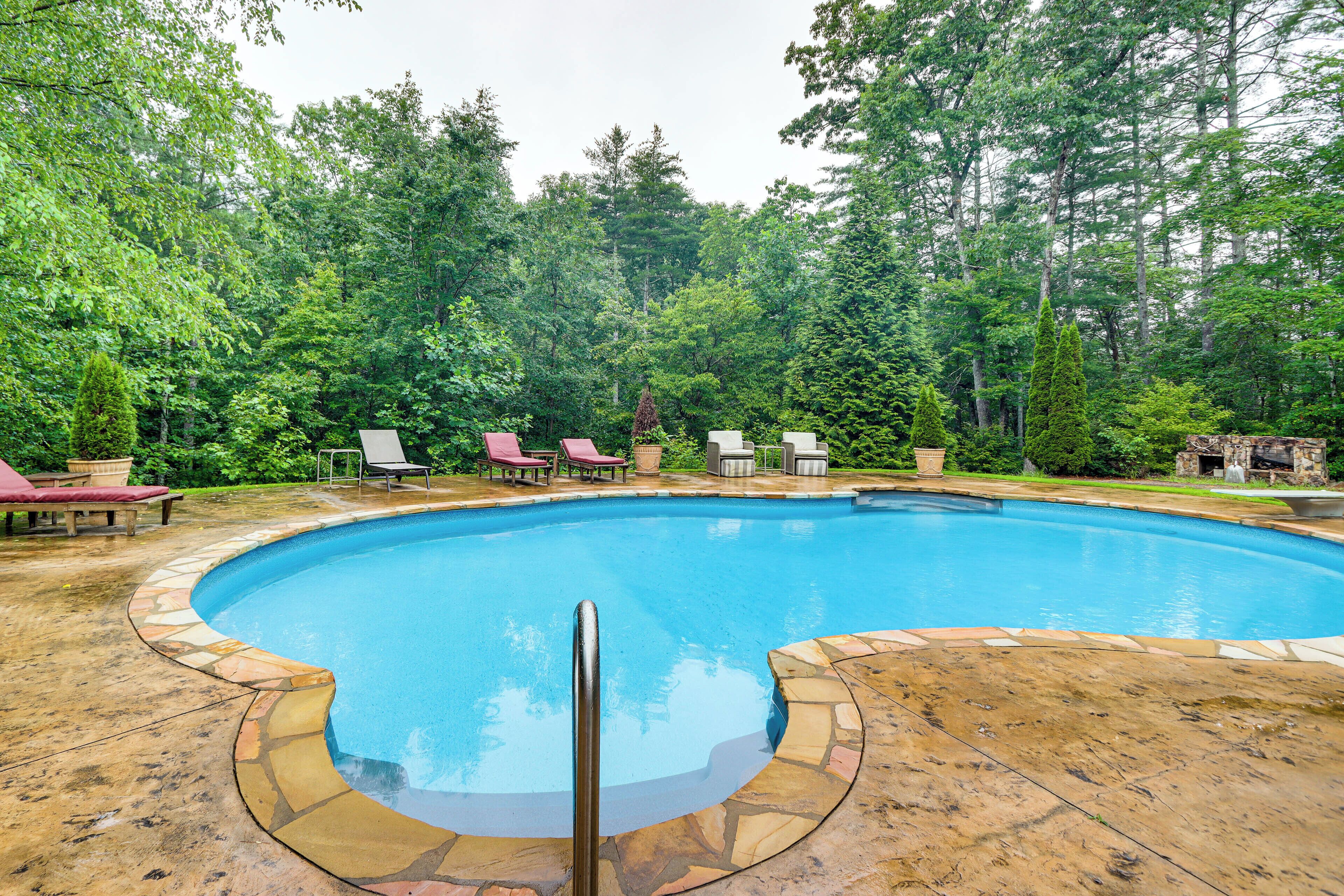 A circular pool with a stone edge, surrounded by lounge chairs and a stone deck.