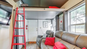 En ombonad inredning med en soffa i läder, röda kuddar, en röd stege och en dörr med en skylt.