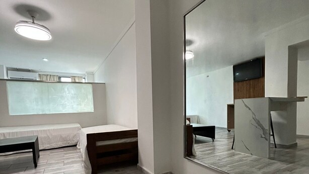 A modern room with a large mirror, a bed, a bench, and a wooden floor. - Suites Lima (Buenos Aires)