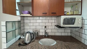 A kitchen with a microwave, sink, and wooden cabinets. - Suites Lima (Buenos Aires)