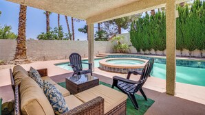 Un espacio al aire libre cubierto con piscina, asientos y vistas a árboles.