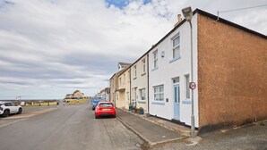 A residential street with houses, a speed limit sign, and parked cars.