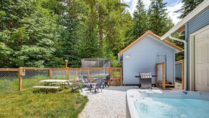A backyard with a hot tub, outdoor seating, a grill, and a fenced play area. - 7 Mi to Mt Rainier NP: Home w/ Private Hot Tub! (Ashford)