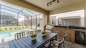 A patio with a pool, outdoor grill, and dining area with chairs and a table. - Amazing 7 bd Summerkitchen Gameroom (Clermont)