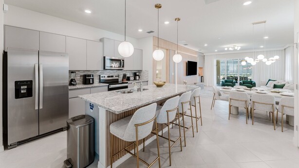 A modern kitchen with stainless steel appliances, a granite countertop island, and bar stools. - Amazing 7 bd Summerkitchen Gameroom (Clermont)