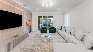 A modern living room with a large flat-screen TV, a sofa, a coffee table, and a patterned rug. - Amazing 7 bd Summerkitchen Gameroom (Clermont)