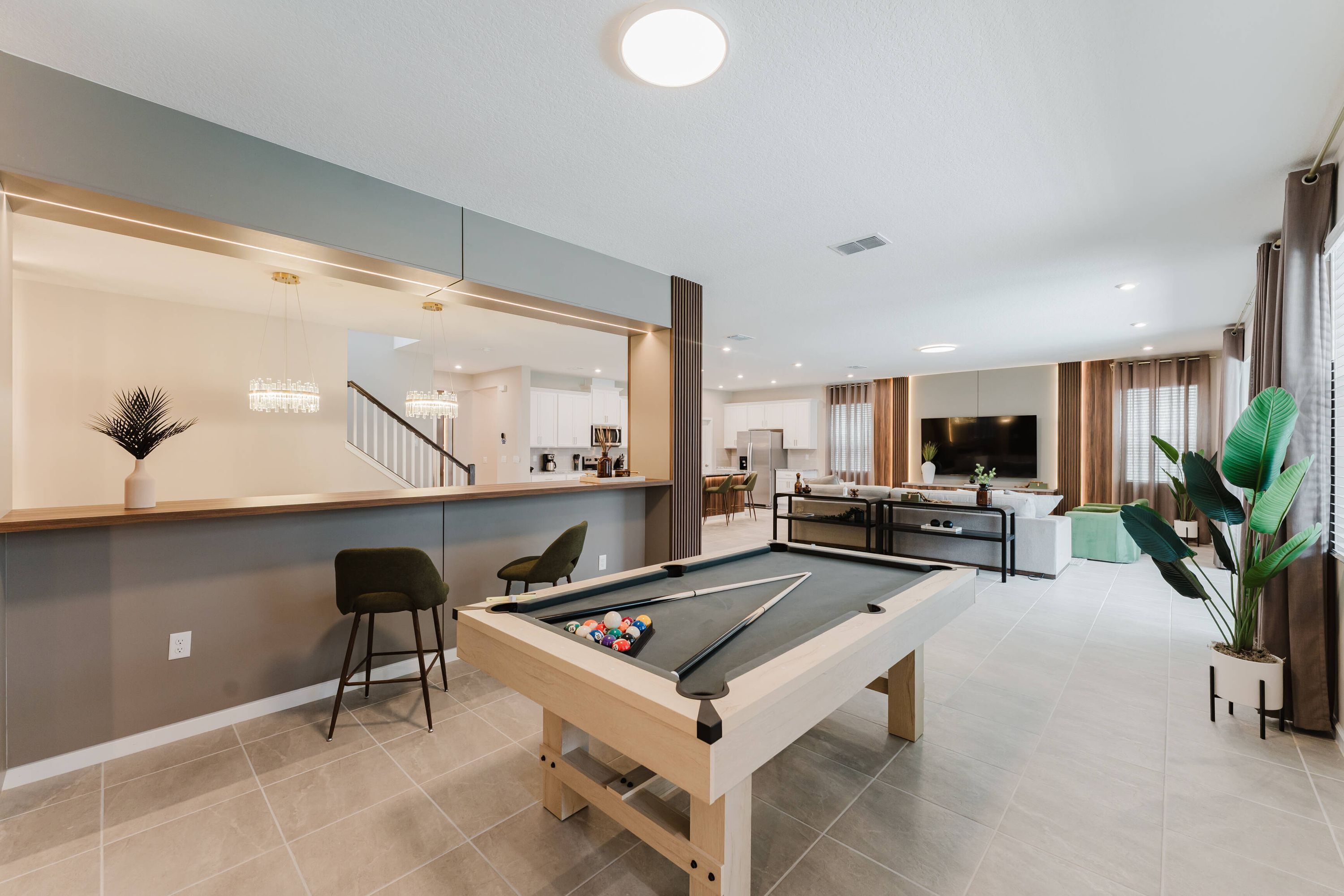 A modern living room with a pool table, a bar area, and a large mirror.