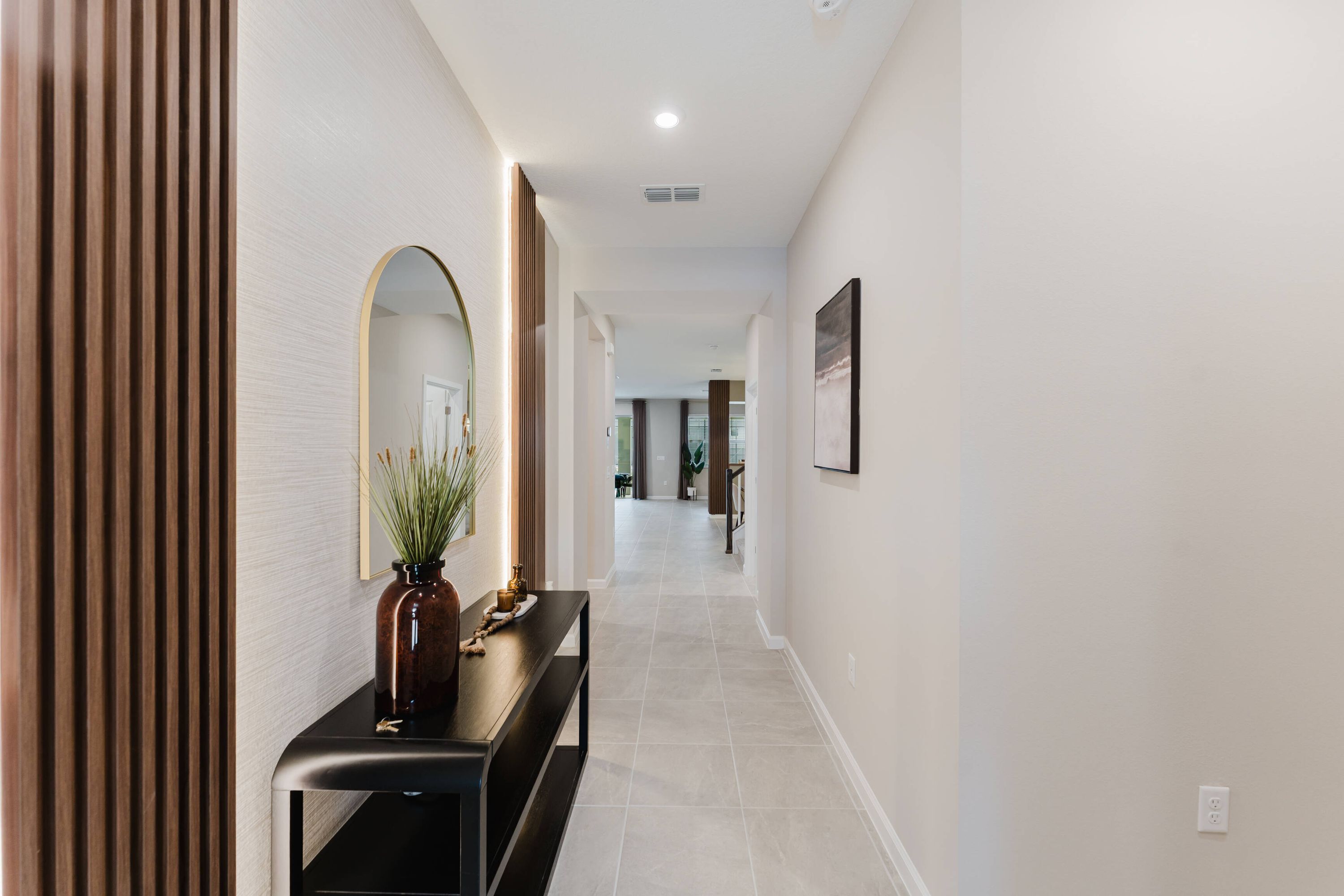 A hallway with a bench, a mirror, and a plant.