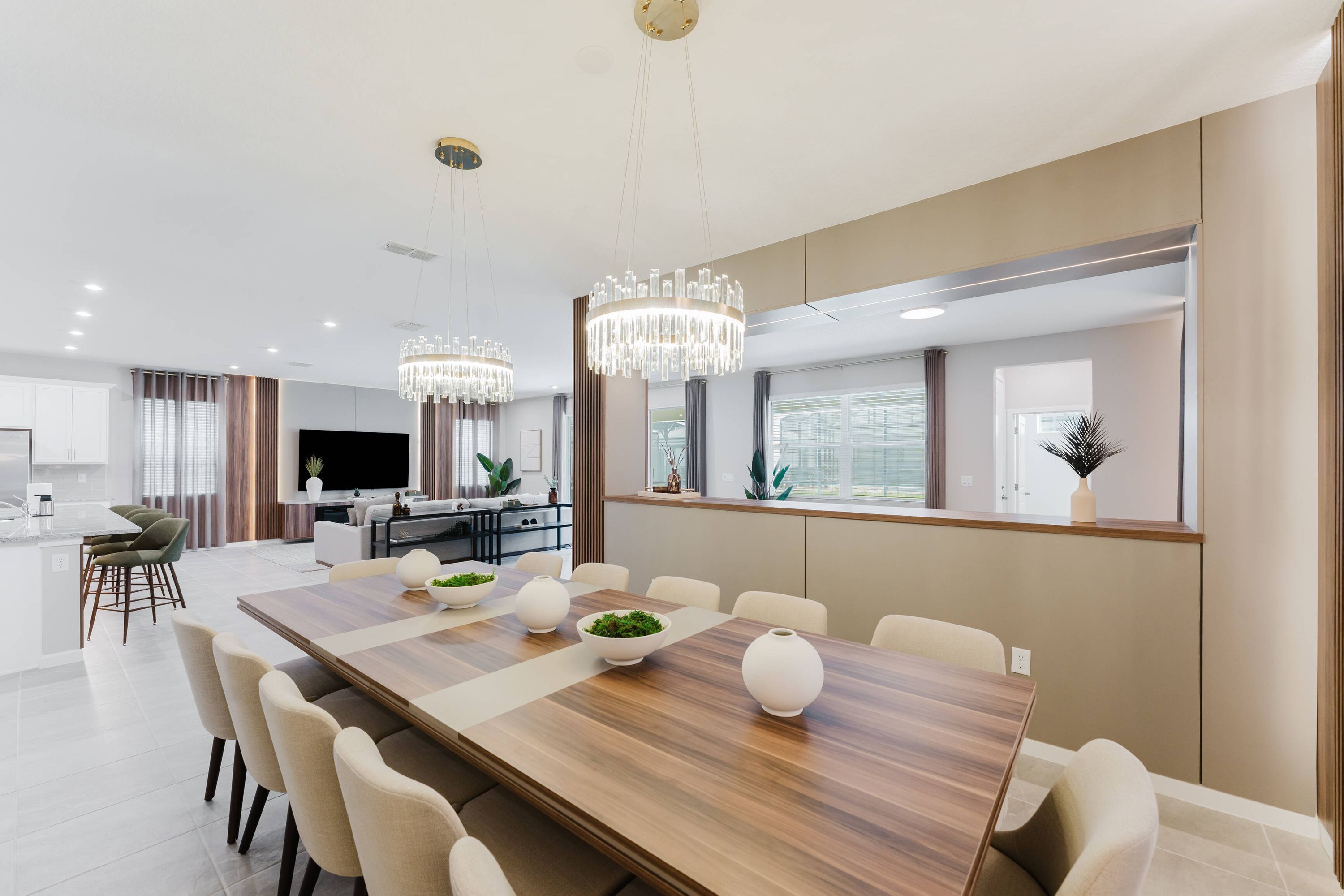 A modern dining area with a long wooden table, multiple chairs, and decorative vases.