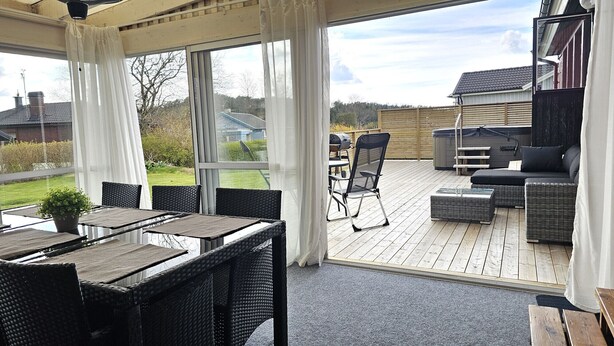 Un patio exterior cubierto con mobiliario de mimbre, una parrilla y un jacuzzi.