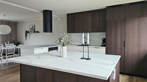 Una cocina moderna con una isla de mármol, armarios de madera oscura y una campana extractora negra.