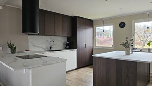 Una cocina moderna con encimera de mármol, lavaplatos integrado, cafetera y armarios de madera.