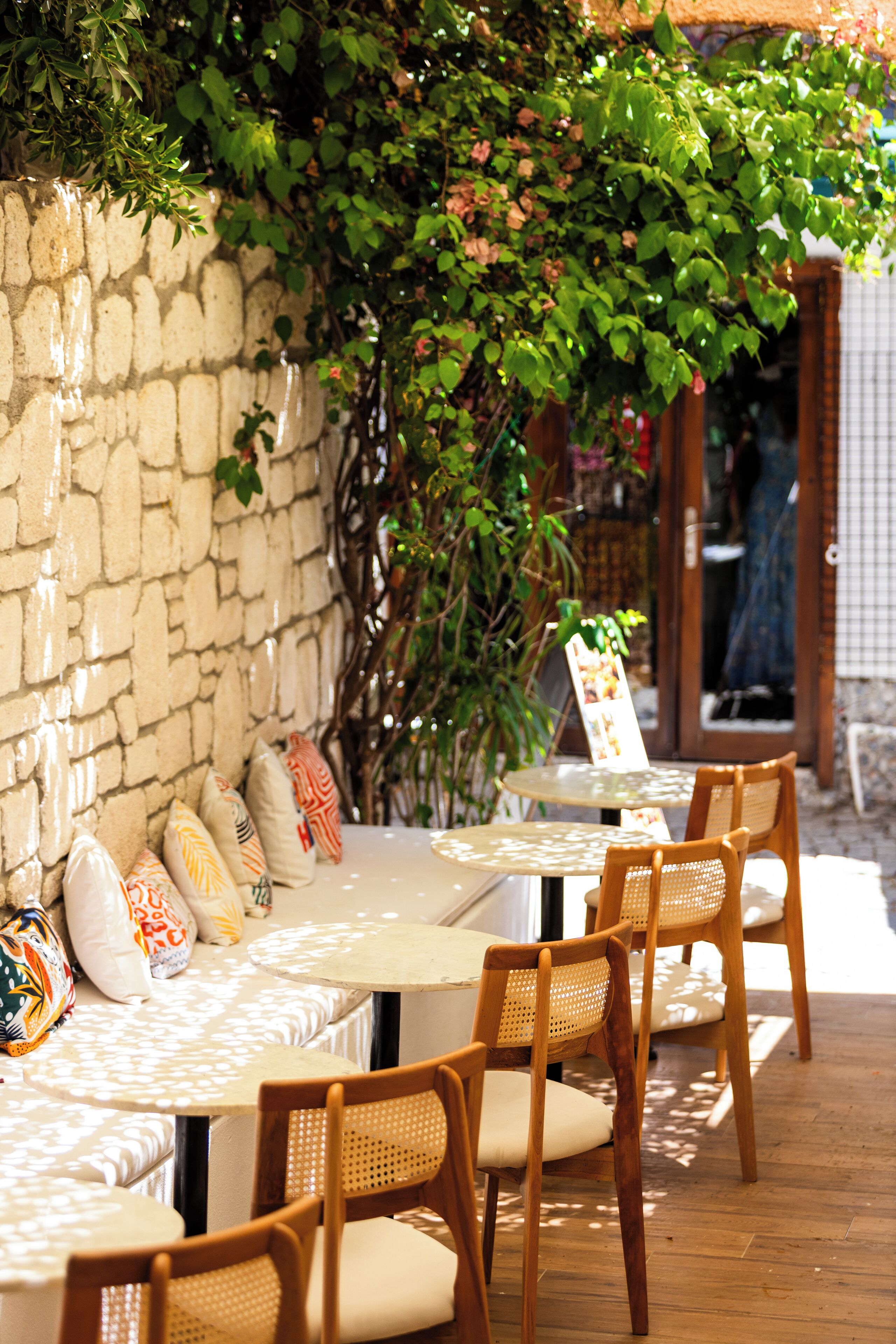 A patio area with a stone wall, wooden chairs, and a table with a menu.