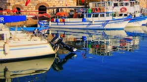 A harbor with boats docked, a stone building, and palm trees. - Casa Fiore (Seferihisar)