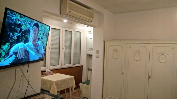Une pièce comprenant une télévision, une table recouverte d’une nappe et une armoire dotée de poignées décoratives.