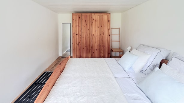 A bedroom with a large bed, wooden wardrobe, and a small bedside table. - Maria's Orchard Cottage - Nature vacation in Slovenia (Rogaška Slatina)
