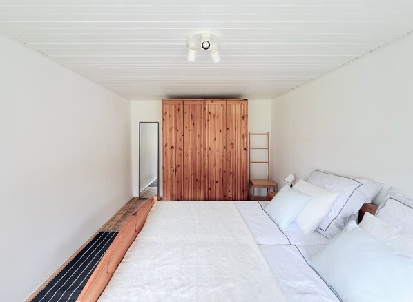 Une chambre à coucher avec un grand lit, une armoire en bois et une petite table de chevet.
