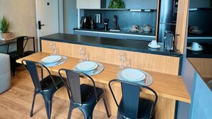 Una cocina moderna con una isla central, sillas negras e iluminación colgante.