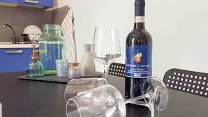 Ett bord med en flaska Vèchia Cantina-vin, två tomma vinglas och en glasburk med en pump.