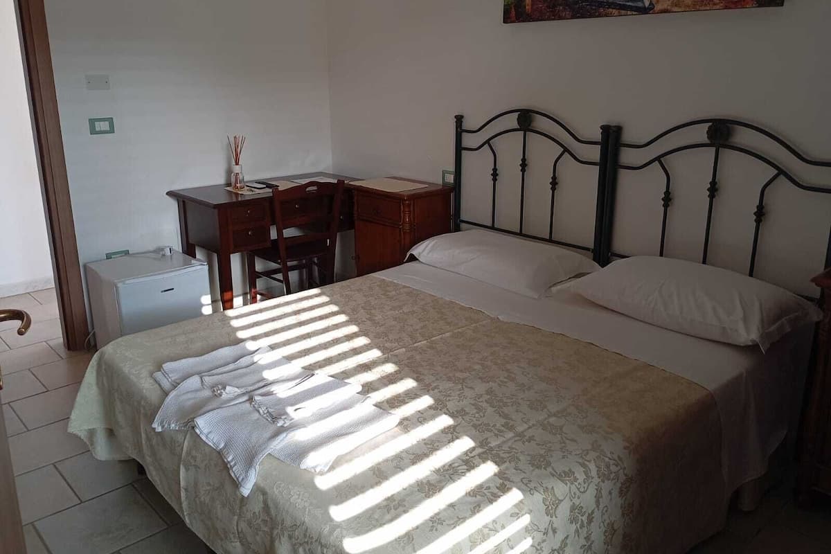 A bedroom with a bed, a desk, and a chair.