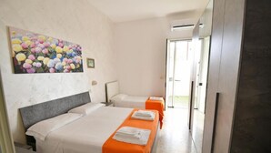 Ein Hotelzimmer mit zwei Betten, einem Bild an der Wand und Blick ins Freie.