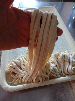 A hand holding a bundle of pasta over a cutting board. - IL Pavone (Nardò)