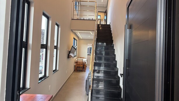 Un interior modern amb una escala, una banca de fusta i una zona de menjador.