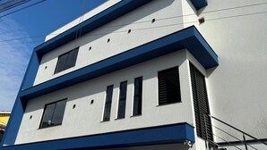 Un edifici modern amb façana blanca i accents blaus, amb diverses finestres i un terrat pla.