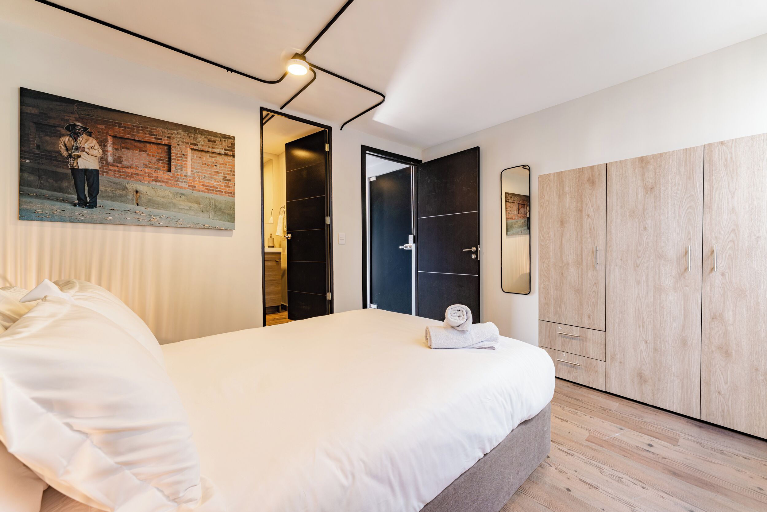 Une chambre à coucher avec un lit, un tableau, une armoire et un miroir.