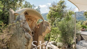 A stone structure with a canopy, surrounded by trees and a mountainous landscape. - Villa Elena - Charming Oasis with heated pool (Sardegna)