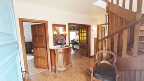 A spacious hallway with a wooden staircase, a wooden chair, and a mirror on the wall.