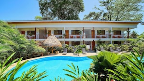 A resort with a pool, multiple balconies, and lush tropical vegetation. - Olinca Boutique Hotel (Cahuita)