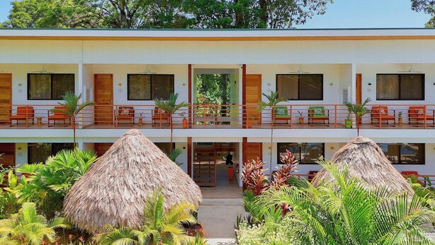 A two-story hotel with balconies, a central entrance, and tropical vegetation. - Olinca Boutique Hotel (Cahuita)