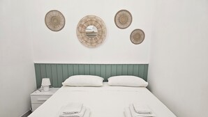 A neatly made bed with two pillows and folded towels, a bedside table with a lamp, and three wall-mounted decorative items. - Retrò holiday home- Pandorea (Sava)