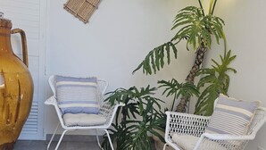 A room with two white wicker chairs with striped cushions, a large woven rug, and a potted plant with large green leaves. - Retrò holiday home- Pandorea (Sava)