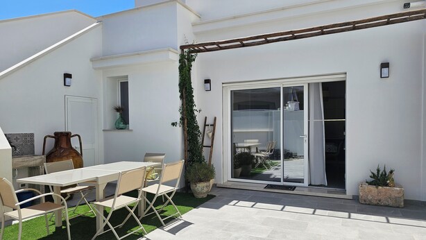 A patio with a table and chairs, a large vase, and a potted plant. - Retrò holiday home- Pandorea (Sava)