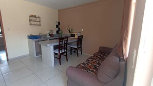 A living room with a sofa, a coffee table, and a dining area with chairs and a small kitchen counter. - Complete apartment in the port of Veracruz, ideal for relaxing! (Veracruz)