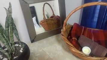A room with a potted plant, a wicker basket, and a sofa with a plaid blanket.