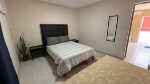 A bedroom with a bed, bedside tables, a potted plant, a mirror, and a door leading to a balcony. - Complete apartment in the port of Veracruz, ideal for relaxing! (Veracruz)