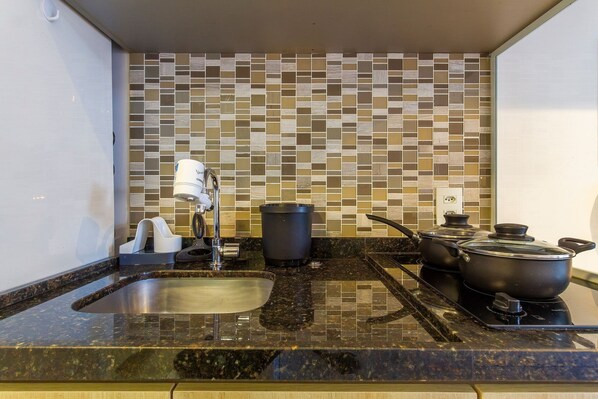 A kitchen with a tiled backsplash, a sink, a stove, and two pots. - Innvista - Is moema (São Paulo)