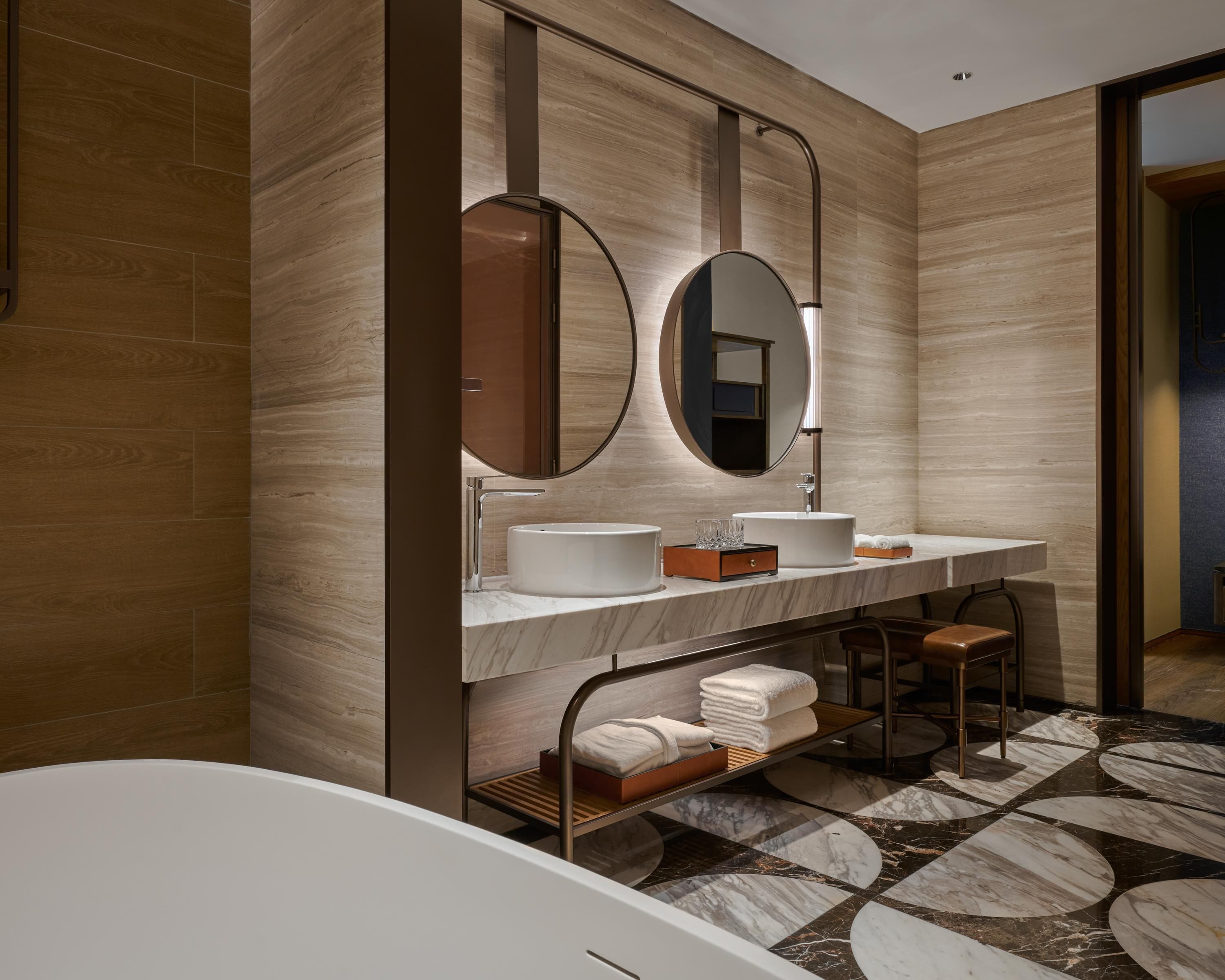 Un baño moderno con una bañera, dos lavamanos, un espejo grande y un mueble de tocador de madera.