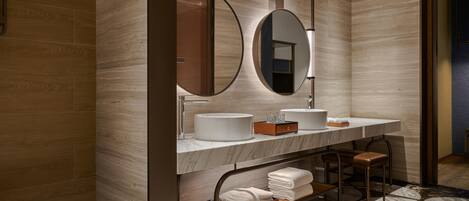 Un baño moderno con una bañera, dos lavamanos, un espejo grande y un mueble de tocador de madera.