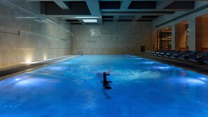 An indoor swimming pool with a dolphin, a sunlit ceiling, and a row of sun loungers. - Thompson Shanghai Expo, by Hyatt (Shanghai)