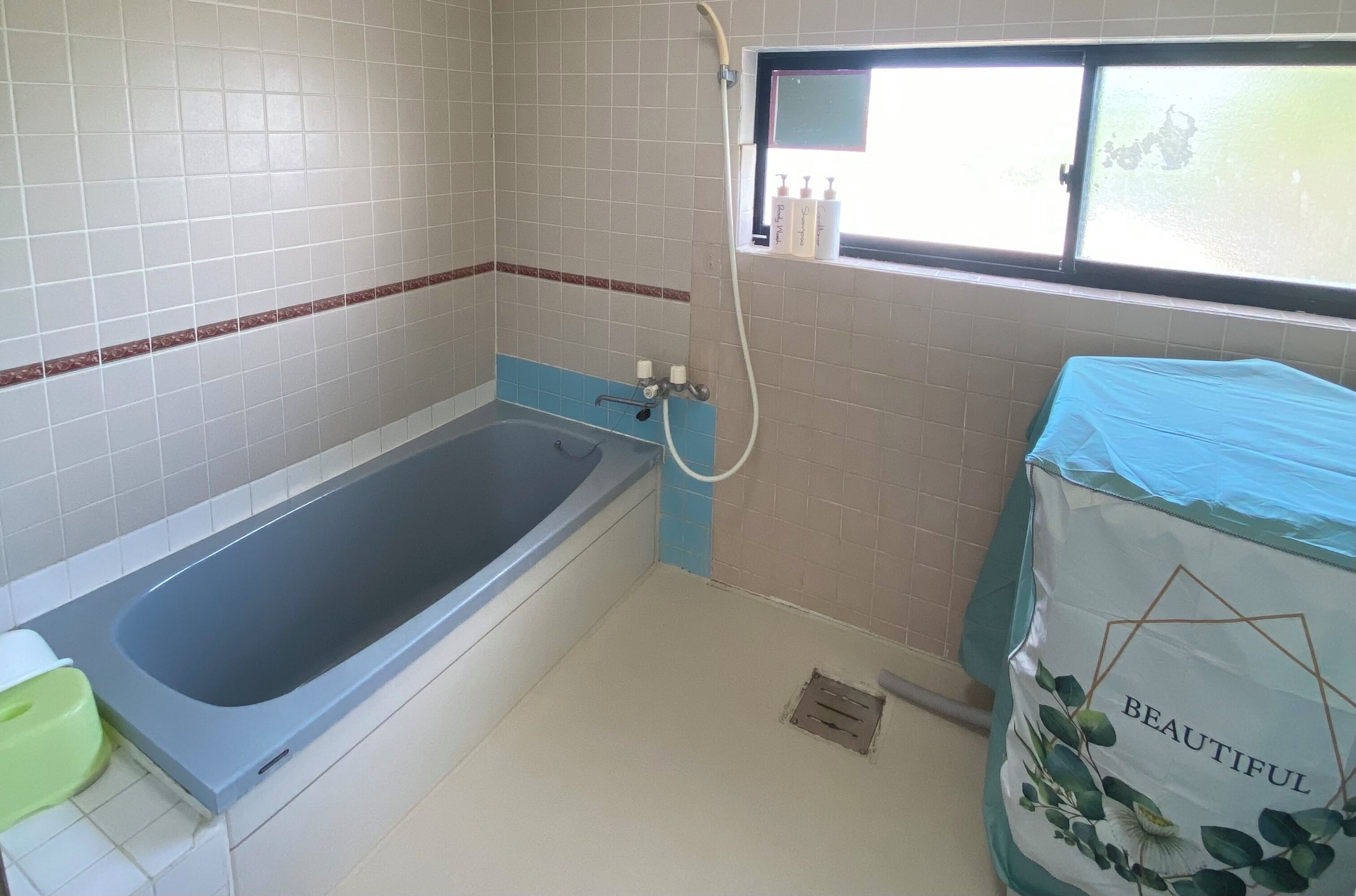 A bathroom with a bathtub, a window with a view, and a shower area.