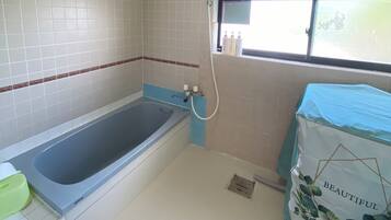 A bathroom with a bathtub, a window with a view, and a shower area.